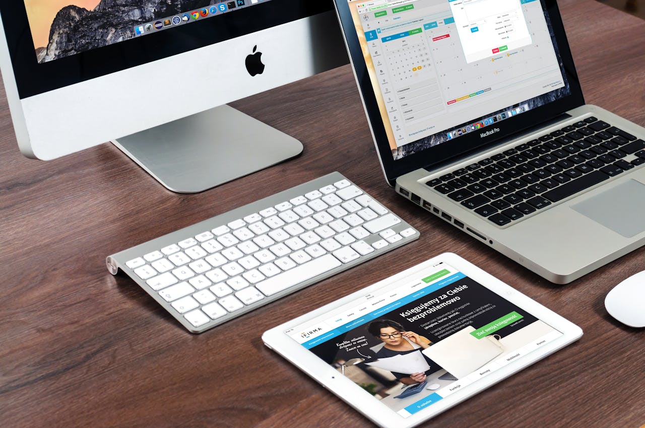 who-we-are A sleek office desk setup featuring Apple devices: iMac, MacBook, and iPad.